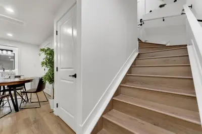 a staircase in a home with white walls and wood floors at 2-bedroom suite close to Amenities and Airport with on pad parking in Leduc