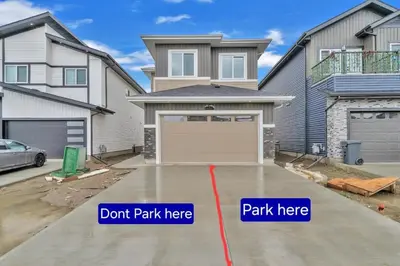 a house with a garage with two signs that say dont park here at 2-bedroom suite close to Amenities and Airport with on pad parking in Leduc