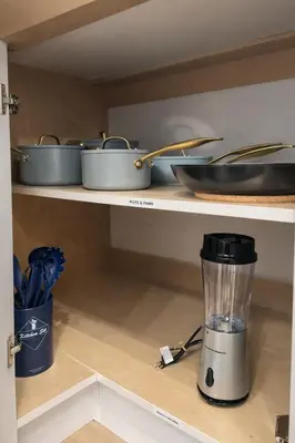 a blender on a shelf with pots and pans at Ocean-Inspired Art Suite in Langford