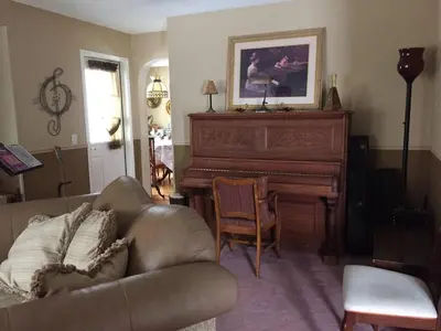 a living room with a couch and a piano at Harmony House short term rental in Okotoks