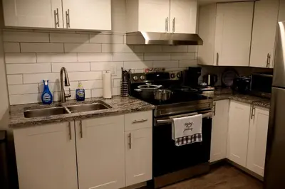 a kitchen with white cabinets and a black stove top oven at Cozy and Private Guest Suite in West Edmonton in Edmonton
