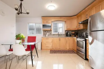 a kitchen with wooden cabinets and a table and a refrigerator at Private 2BR 2Bath Suite - Sunset Vancouver in Vancouver