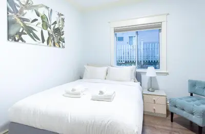 a bedroom with a white bed and a blue chair at 3Beds Ground-Level Private Suite in Burnaby in Burnaby