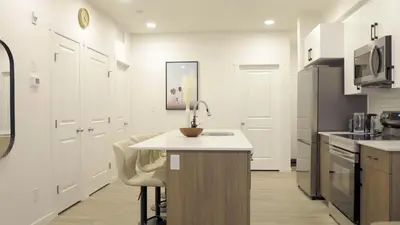 a kitchen with white cabinets and a table and chairs at A Touch of the Tropics-Cozy Warm 2BR Stay in Edmonton