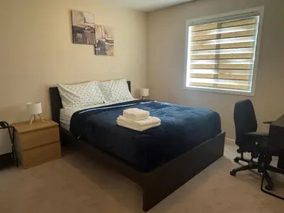 a bedroom with a bed with blue sheets and a window at Peace Home in Calgary