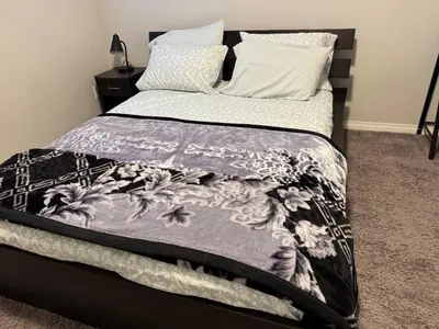 a bed with a black and white comforter and pillows at Quiet Comfortable 1-Bedroom in Calgary