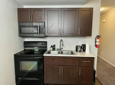 a kitchen with a sink and a stove and microwave at Quiet Comfortable 1-Bedroom in Calgary