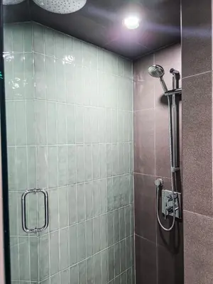 a bathroom with a shower with green tiles at Copper Rose Retreat - Mountain B&B in Invermere