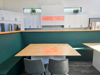 a table in a kitchen with two chairs and a counter at Copper Rose Retreat - Mountain B&B in Invermere