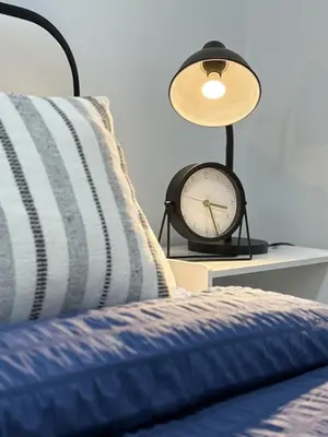a clock sitting on a table next to a bed at Private 2BR Lake Suite - Chestermere - Sleeps 6 in Chestermere
