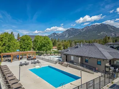 an image of a swimming pool with mountains in the background at Bighorn Meadows Condos by StayIn in Radium Hot Springs