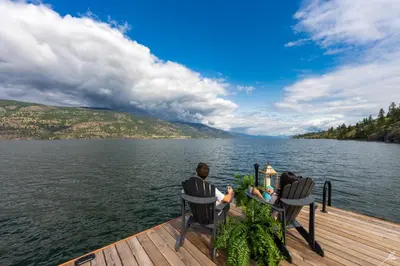 two people sitting on a dock overlooking a body of water at Chateau Okanagan in Kelowna