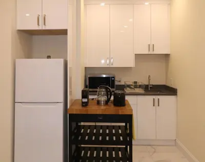 a kitchen with white cabinets and a white refrigerator at SixPine - One bedroom suite in Vancouver