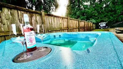 a bottle of wine and two wine glasses on a table at Emerald 3Bed 1bath Rancher 2C-D EvEs Spa BBQ RKE in Langley