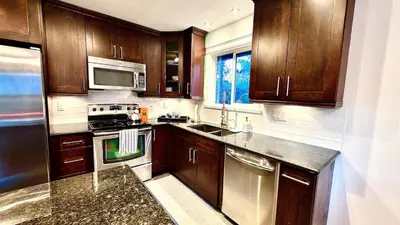 a kitchen with wooden cabinets and stainless steel appliances at Emerald 3Bed 1bath Rancher 2C-D EvEs Spa BBQ RKE in Langley
