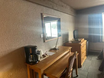 a room with a desk with a mirror and a television at Logan Lake Hotel in Logan Lake