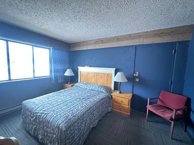 a blue bedroom with a bed and a red chair at Logan Lake Hotel in Logan Lake
