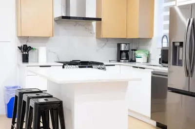 a kitchen with white cabinets and a counter with stools at Elegant Stylish Modern Residence in Vancouver