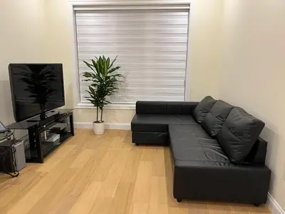 a black leather couch in a living room with a television at SixPine - New 2Br Suite in Vancouver