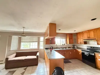 a kitchen with wooden cabinets and a couch in it at Cozy Private Queen room Scott Rd in Bélanger