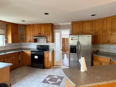 a kitchen with wooden cabinets and a stainless steel refrigerator at Cozy Private Queen room Scott Rd in Bélanger