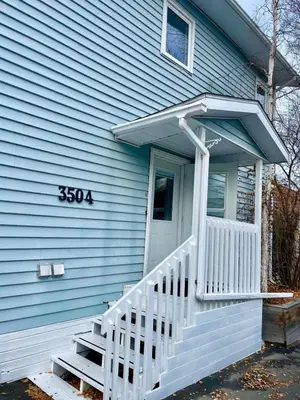 a blue house with a white porch and stairs at Aurora views from 2 br apartment by lake in Yellowknife