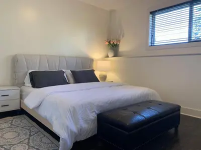 a bedroom with a large white bed with a ottoman at Modern 2BR Retreat Near West Edmonton Mall in Edmonton