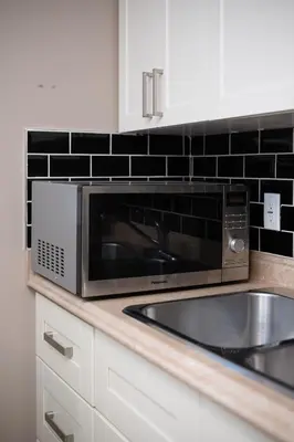 a kitchen counter with a microwave and a sink at Modern 2BR Suite | 10 Mins to YVR & Canada Line in Vancouver