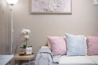 a white couch with pink and blue pillows in a living room at Modern 2BR Suite | 10 Mins to YVR & Canada Line in Vancouver