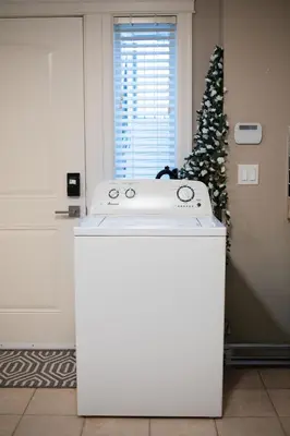 a white washing machine in a room with a christmas tree at Modern 2BR Suite | 10 Mins to YVR & Canada Line in Vancouver