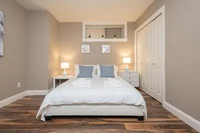 a bedroom with a white bed and two lamps at Modern 2BR Suite | 10 Mins to YVR & Canada Line in Vancouver