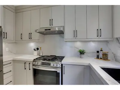 a white kitchen with a stove and white cabinets at BRAND NEW LUXURY 4 Beds 4 baths Home Langley Perfect for Families and Groups in Langley