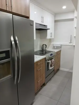 a kitchen with stainless steel appliances and wooden cabinets at Aeropuerto basement in Calgary