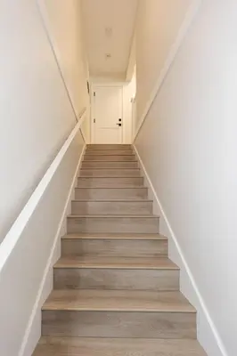 a staircase in a house with white walls and wooden floors at Cozy Corner on Trumpeter in Colwood
