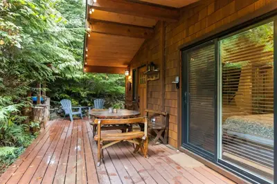 a wooden deck with a table and chairs on it at JDF Waystation with Bunkhouse - Pet Friendly - sleeps 6 in Port Renfrew