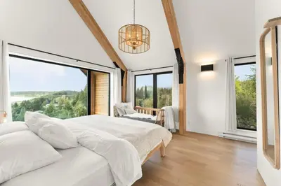 a bedroom with a large bed and large windows at Hot Tub & Amazing Ocean View -The Simple Peak - Non pet friendly in Port Renfrew