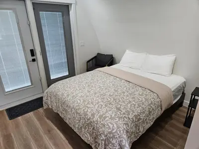 a bedroom with a bed and two windows at Pet Friendly cozy cabin getaway with Kitchenette and Private Bath in Port Renfrew