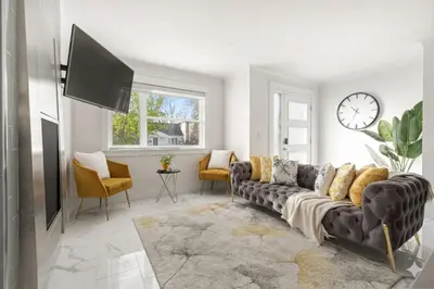 a living room with a couch and a clock on the wall at Family friendly Lux house Near University Train Hospital in Edmonton