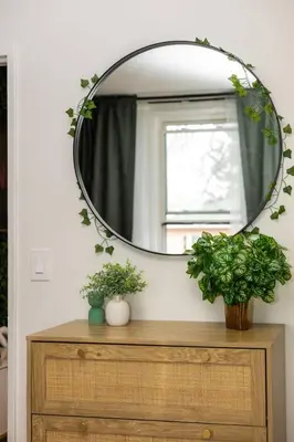 a mirror on top of a wooden dresser with plants at Quiet & Walkable - Stampede, BMO, Nightlife & Eats in Calgary