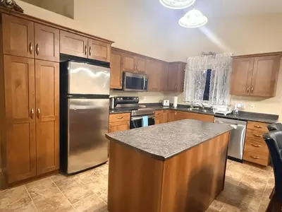 a kitchen with wooden cabinets and a stainless steel refrigerator at Gans Home - 5 Bedroom Residence in Lloydminster