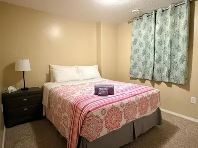 a bedroom with a bed with a pink blanket at Gans Home - 5 Bedroom Residence in Lloydminster