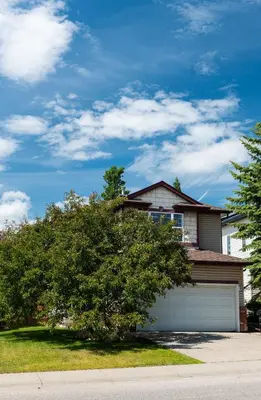 a house with a tree in front of a garage at Family Retreat Hot Tub Banff and Calgary DT Access in Calgary
