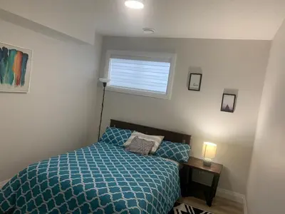 a bedroom with a bed with a blue comforter and a window at Beautiful one Bedroom Bsmnt suite with sep Entrance in Edmonton