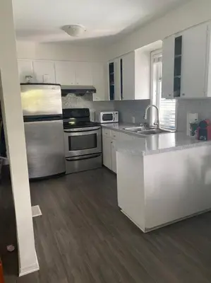 a kitchen with white cabinets and stainless steel appliances at Quiet-comfy 4 bedroom house on a tree lined street in Kitsilano in Vancouver
