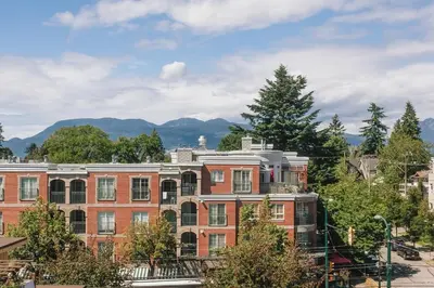 a large brick building with mountains in the background at Private Penthouse Beside Beach with Rooftop Patio in Vancouver