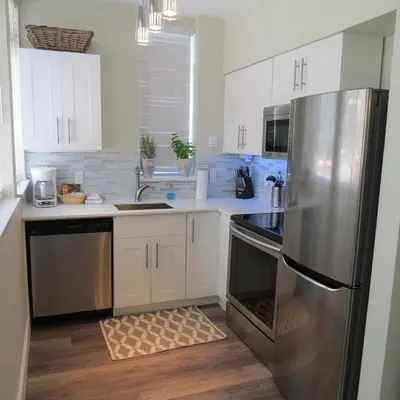 a kitchen with white cabinets and a stainless steel refrigerator at Private Penthouse Beside Beach with Rooftop Patio in Vancouver