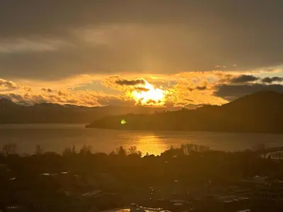 a sunset over a body of water with the sun setting at Signature Iconic Lakeview Downtown 2-Bedroom Loft in Kelowna