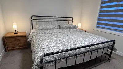 a bedroom with a bed and two lamps on a night stand at Heartland Stays - Brand New 3 Bed Room Cozy Home in Cochrane