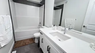 a white bathroom with a sink and a toilet at Heartland Stays - Brand New 3 Bed Room Cozy Home in Cochrane