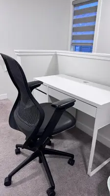 a desk with a black chair and a white desk at Heartland Stays - Brand New 3 Bed Room Cozy Home in Cochrane